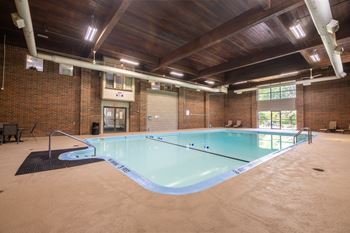 A large indoor swimming pool with a wooden ceiling and brick walls.